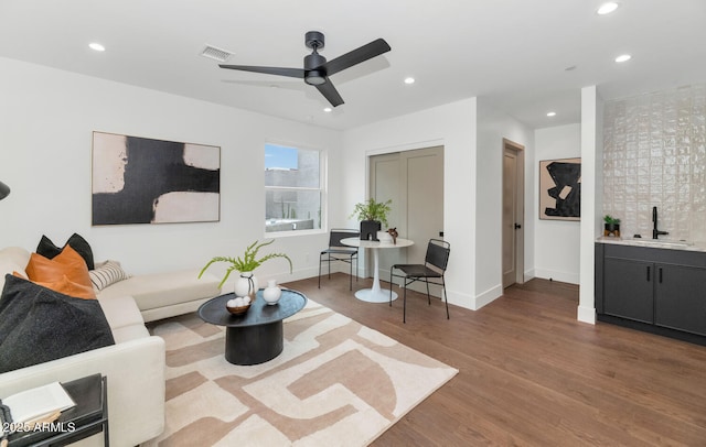 living room featuring dark hardwood / wood-style floors, ceiling fan, and sink