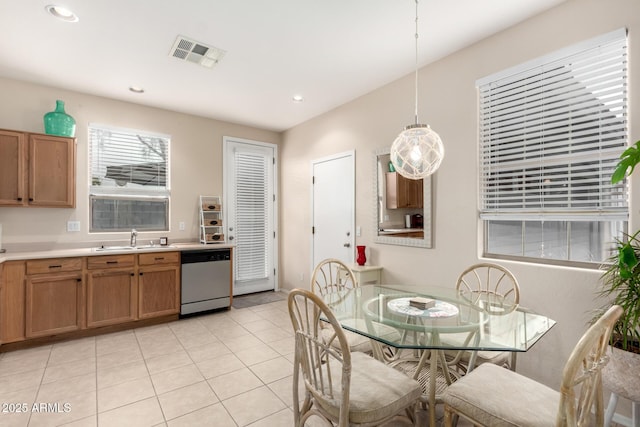 kitchen with dishwasher, light tile patterned floors, decorative light fixtures, and sink