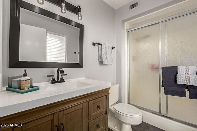 full bath featuring visible vents, toilet, vanity, and a shower stall