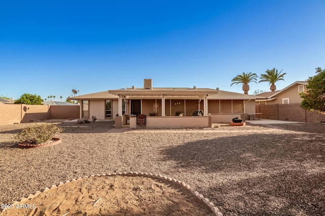 rear view of property with a sunroom, a fenced backyard, stucco siding, and a patio
