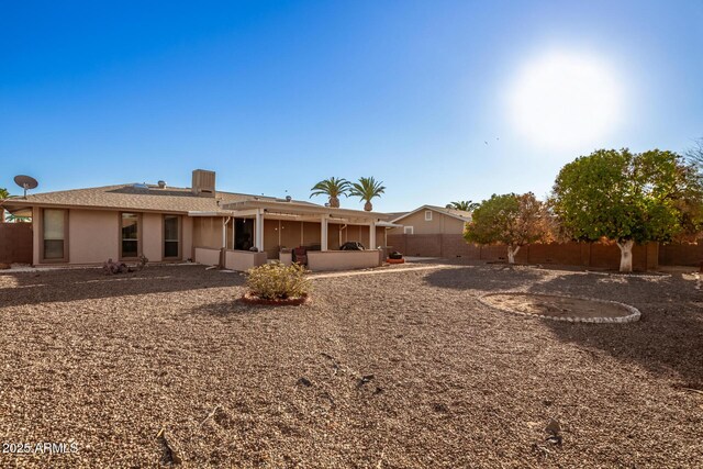 rear view of property with stucco siding, a fenced backyard, and a patio