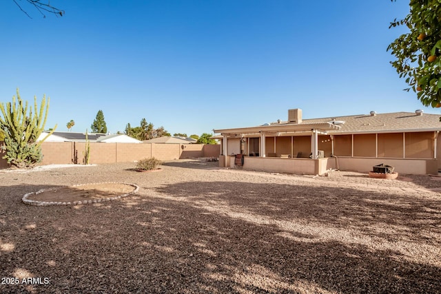 back of house featuring a sunroom, a fenced backyard, a chimney, and central AC unit