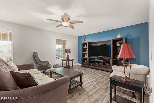living room featuring light wood-type flooring, baseboards, and a ceiling fan