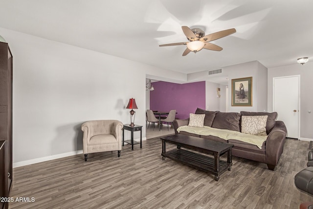 living room with a ceiling fan, visible vents, baseboards, and wood finished floors