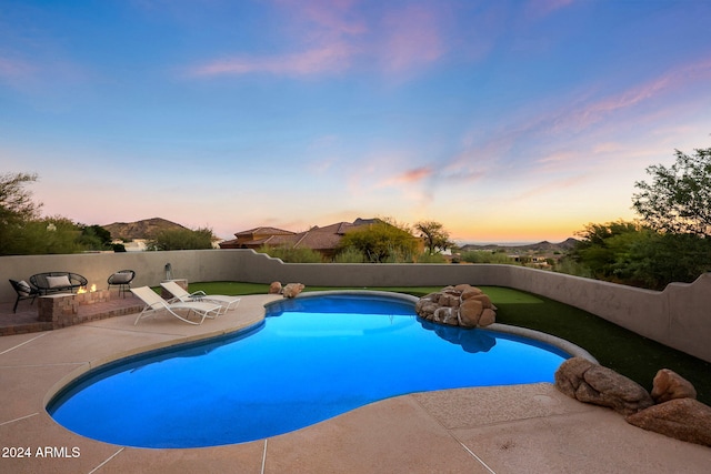 pool at dusk featuring a patio and a mountain view