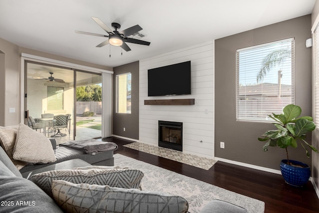 living room with ceiling fan, a large fireplace, and dark hardwood / wood-style flooring