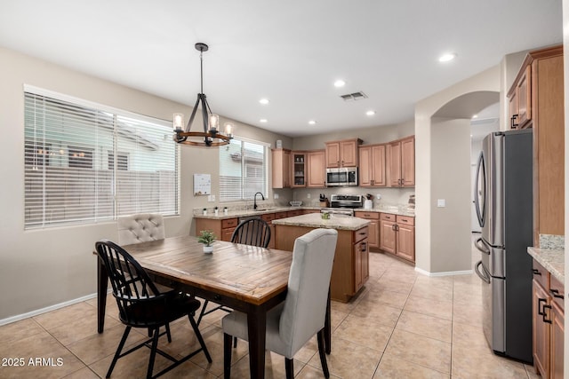 dining space featuring light tile patterned flooring, sink, and a notable chandelier