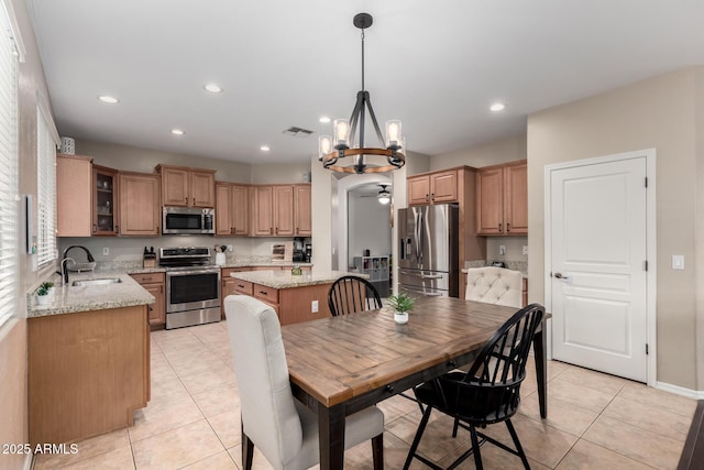 dining space featuring light tile patterned flooring, ceiling fan with notable chandelier, and sink