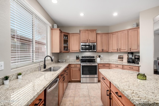 kitchen with appliances with stainless steel finishes, sink, light tile patterned floors, and light stone counters