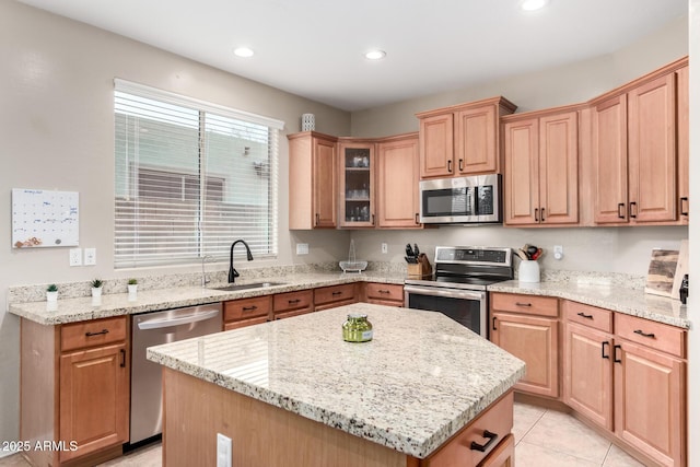 kitchen featuring light tile patterned flooring, sink, light stone counters, appliances with stainless steel finishes, and a kitchen island