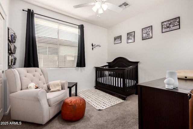 bedroom with a nursery area, ceiling fan, and carpet floors