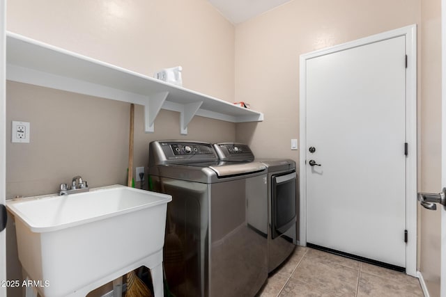 clothes washing area featuring sink, washer and dryer, and light tile patterned floors