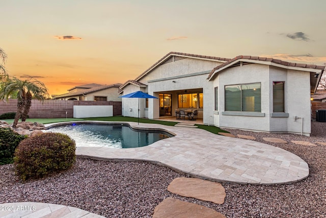 pool at dusk with central air condition unit and a patio area