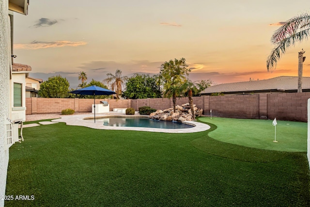 yard at dusk with a fenced in pool and a patio area