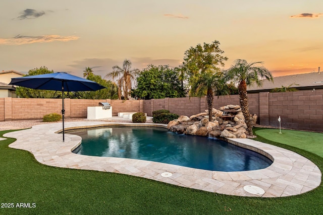 pool at dusk with a patio area and an outdoor kitchen