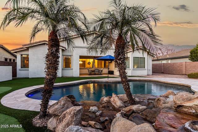 pool at dusk featuring a patio