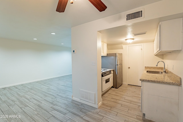 kitchen with sink, white cabinetry, white electric stove, ceiling fan, and light stone countertops