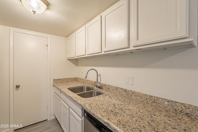 kitchen with sink, light stone countertops, a textured ceiling, white cabinets, and light wood-type flooring