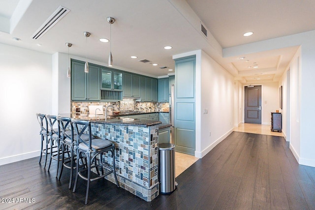 kitchen with kitchen peninsula, backsplash, decorative light fixtures, and dark hardwood / wood-style flooring