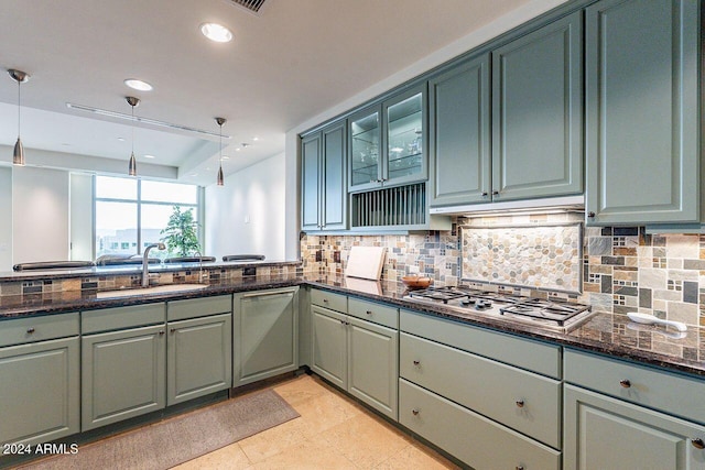 kitchen featuring green cabinetry, sink, dark stone counters, stainless steel gas stovetop, and decorative light fixtures