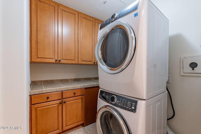 washroom featuring cabinets and stacked washer / drying machine