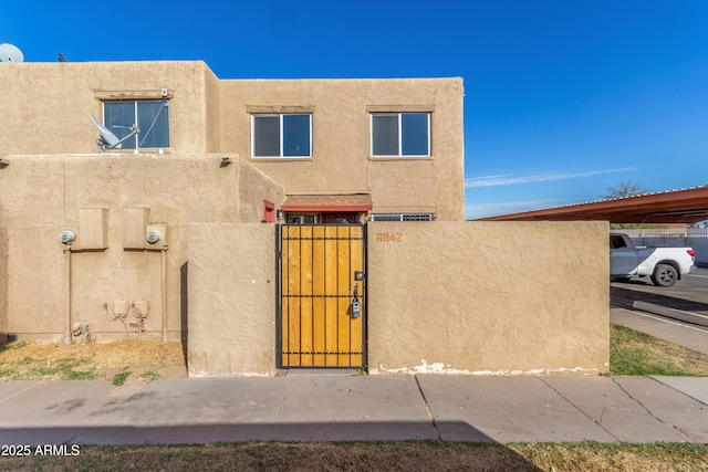 southwest-style home featuring a fenced front yard, a gate, and stucco siding