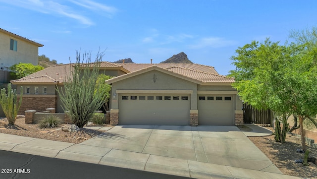 6133 W Fetlock Ter, Phoenix, AZ 85083 - view of front facade with stucco siding, a tiled roof, driveway, a garage, and stone siding