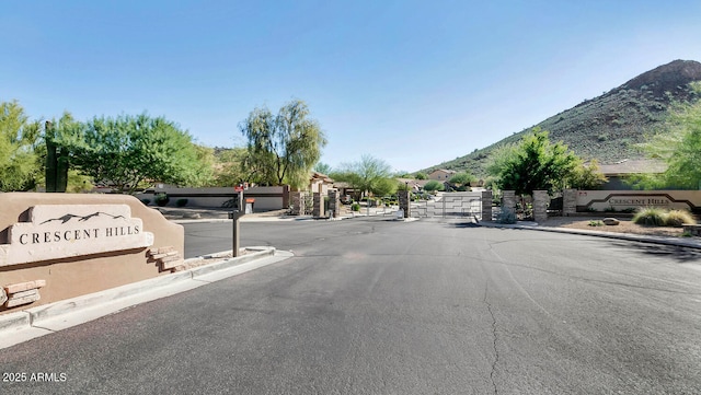 6133 W Fetlock Ter, Phoenix, AZ 85083 - view of asphalt road with a mountain view, a gated entry, curbs, and a gate