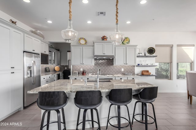 17756 E Silver Sage Ln, Rio Verde, AZ 85263 - kitchen featuring stainless steel fridge, under cabinet range hood, tasteful backsplash, a sink, and a kitchen breakfast bar