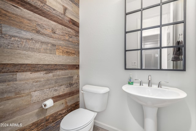 bathroom with toilet and wood walls