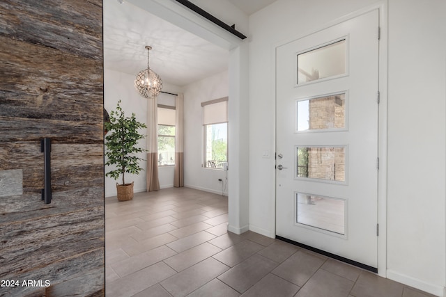 foyer featuring tile patterned floors, an inviting chandelier, and a barn door