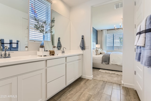 ensuite bathroom with a sink, double vanity, visible vents, wood finished floors, and connected bathroom