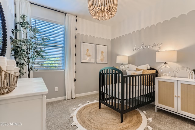 bedroom with a chandelier, a nursery area, carpet flooring, and baseboards