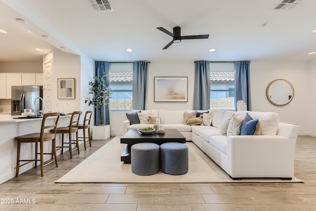 living area featuring plenty of natural light, visible vents, and ceiling fan