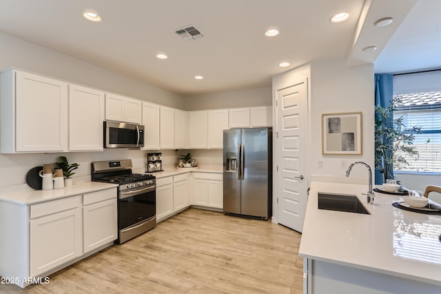 kitchen with a sink, stainless steel appliances, light countertops, visible vents, and recessed lighting