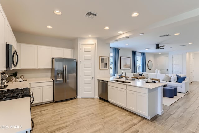 kitchen with stainless steel appliances, a peninsula, visible vents, and a sink