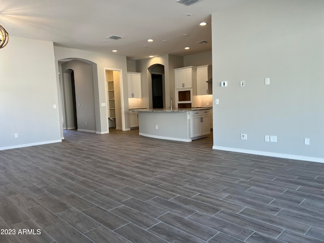 unfurnished living room featuring sink and dark hardwood / wood-style flooring