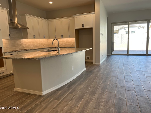 kitchen featuring wall chimney range hood, white cabinets, sink, and dark hardwood / wood-style flooring