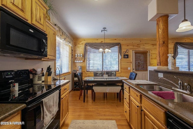 kitchen featuring hanging light fixtures, black appliances, and wood walls