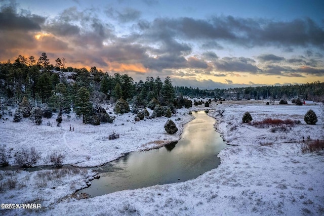 view of snow covered land with a water view