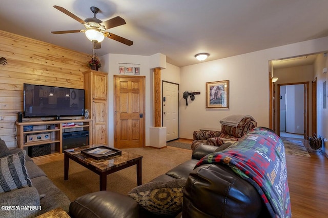 living room with ceiling fan and wooden walls