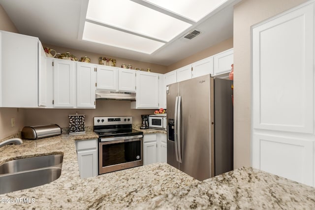 2941 N Oregon St Unit 12, Chandler, AZ 85225 - kitchen featuring appliances with stainless steel finishes, under cabinet range hood, a sink, light stone countertops, and white cabinets