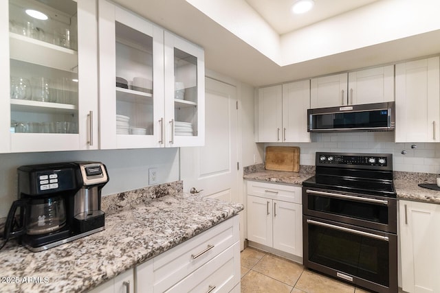 kitchen featuring tasteful backsplash, light tile patterned floors, double oven range, and white cabinetry