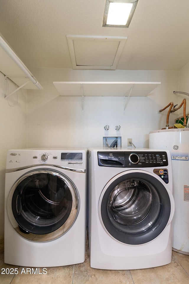 clothes washing area with laundry area, light tile patterned floors, separate washer and dryer, and water heater