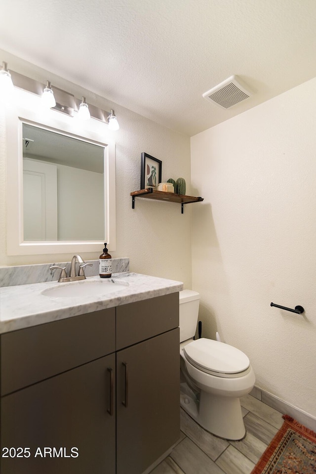 bathroom featuring vanity, toilet, visible vents, and a textured ceiling