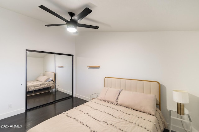 bedroom with a ceiling fan, wood finished floors, baseboards, and a closet