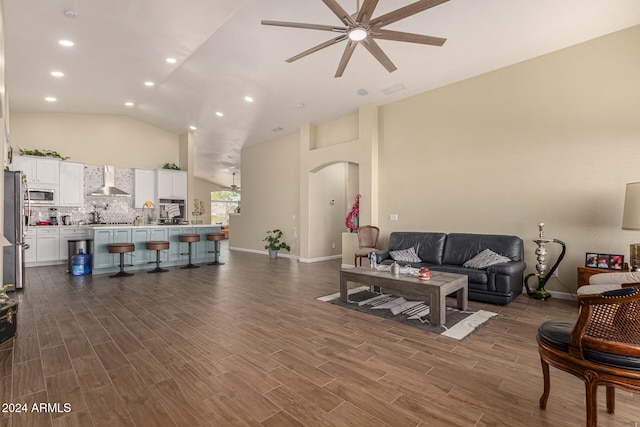 living room featuring dark wood-type flooring, ceiling fan, and vaulted ceiling