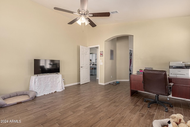 home office with dark wood-type flooring, ceiling fan, and high vaulted ceiling