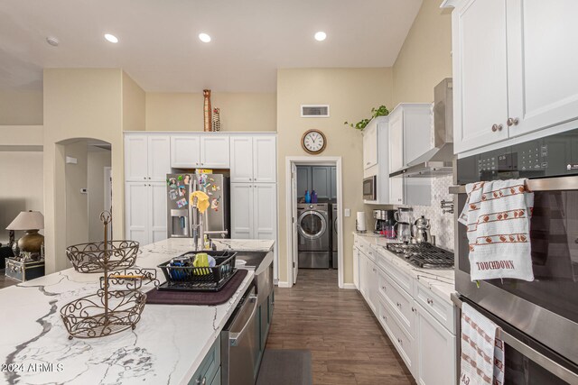 kitchen featuring appliances with stainless steel finishes, white cabinetry, wall chimney exhaust hood, dark wood-type flooring, and light stone counters