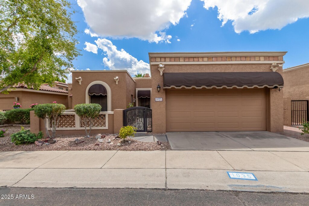 view of front of property with stucco siding, driveway, a fenced front yard, and an attached garage